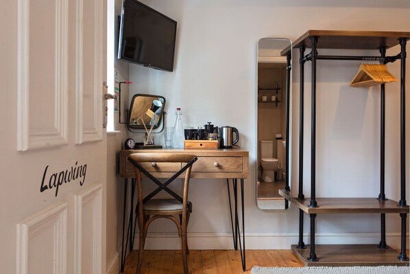 A compact, modern bedroom with a wooden desk, a chair, a mirror, and a TV mounted on the wall. - Three Swallows (Holt)