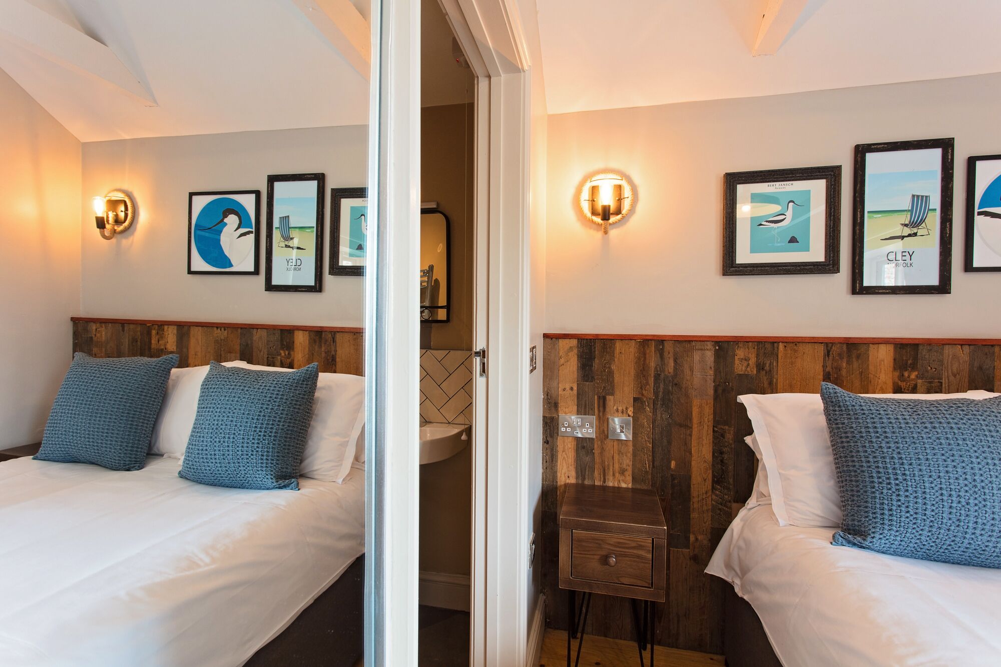 Ein Hotelzimmer mit zwei Betten, Holz-Kopfteilen und Wandbildern.