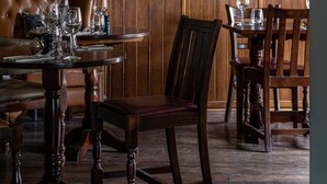 A dining area with a round table, chairs, and a leather sofa. - Three Swallows (Holt)