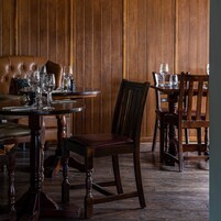 A dining area with a round table, chairs, and a leather sofa.