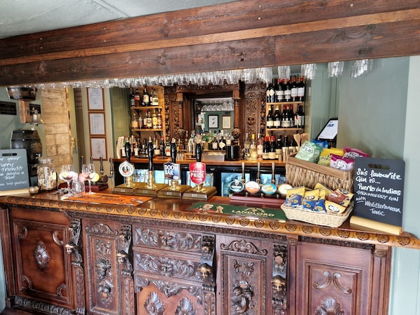Zona de bar con decoración de madera, una variedad de botellas y un menú en la pizarra.