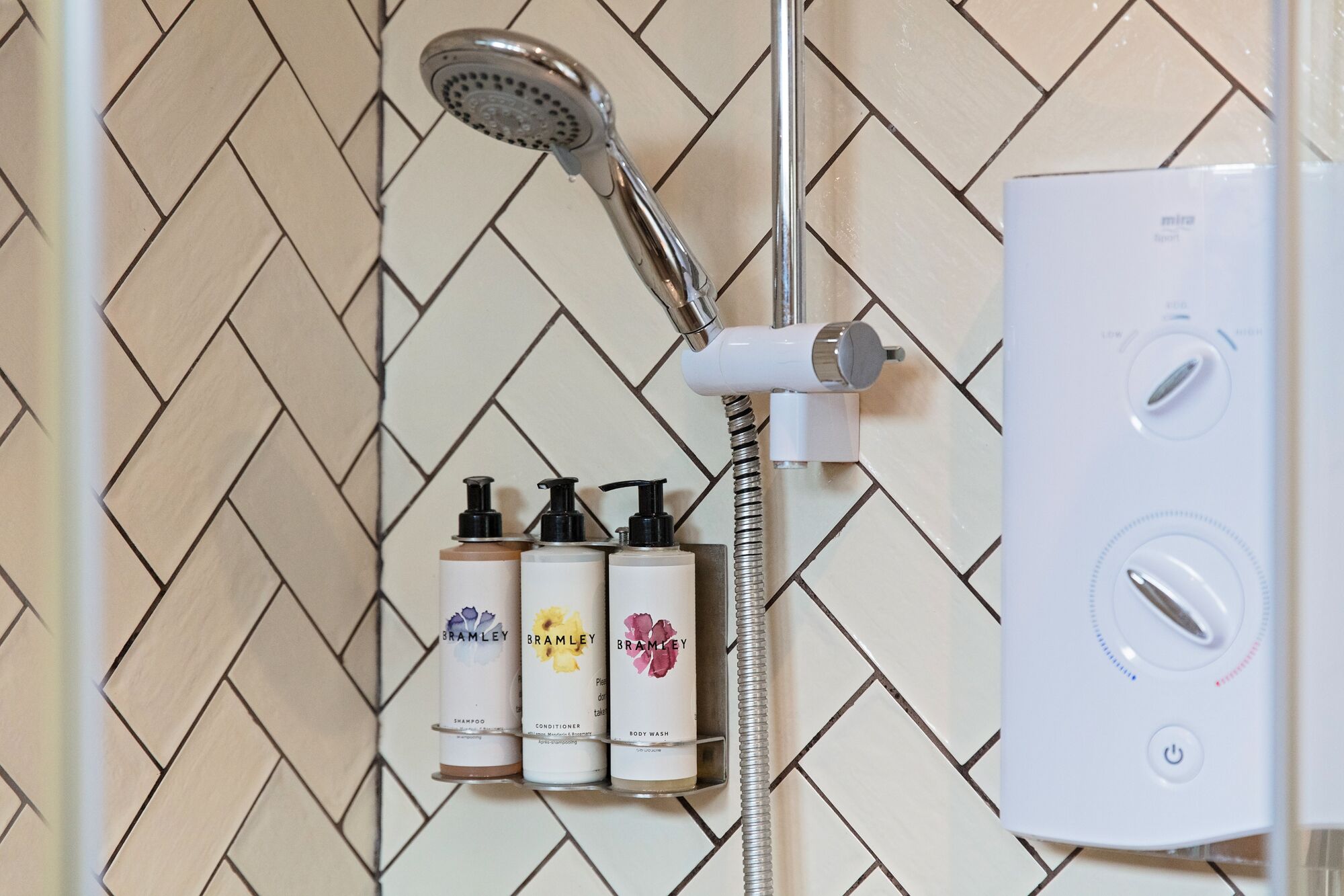 Un baño con ducha, dispensador de jabón en la pared y calentador de agua blanco.