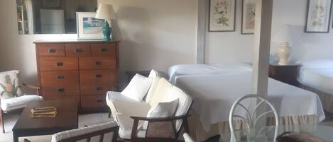 A hotel room with a bed, a desk, a chair, a dresser, and a dining table.