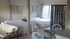 A room with two beds, a dining table with chairs, and a ceiling fan. - A rare combination of central location convenience & private island seclusion  (George Town)