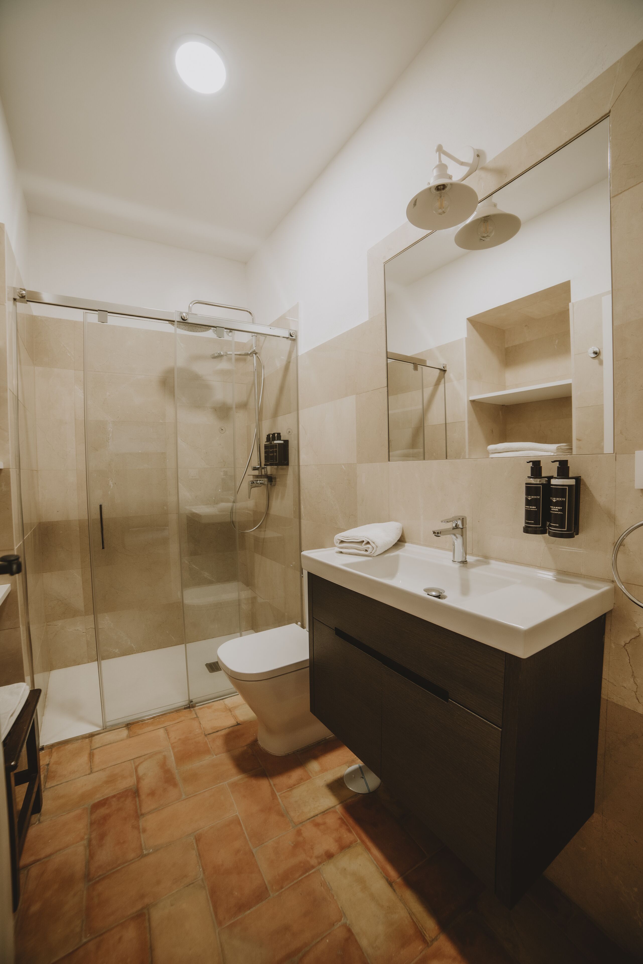 Un baño moderno con ducha envuelta en vidrio, un lavabo blanco y un espejo grande.