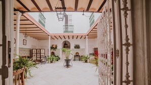 Un amplio patio con techo alto, plantas en macetas y una fuente central.
