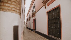 Un estrecho callejón adoquinado flanqueado por edificios con paredes blancas y detalles en rojo.
