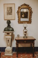 Un busto, un espejo y una mesa con una lámpara.