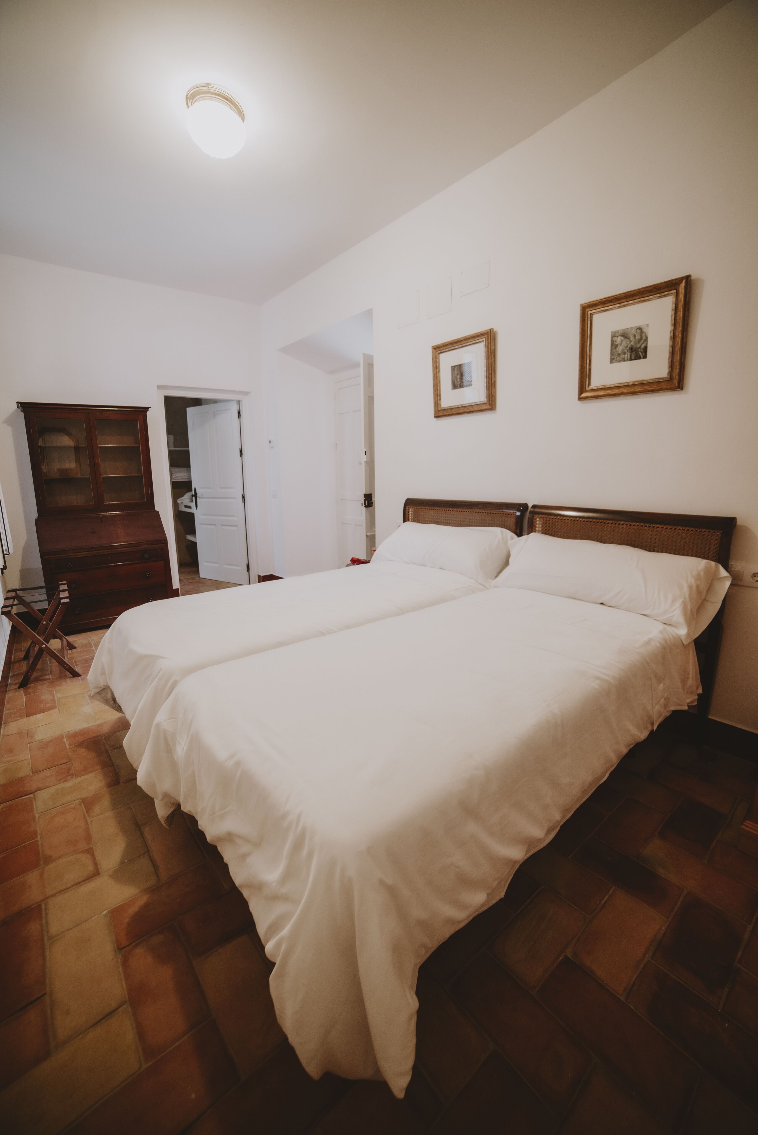 A bedroom with a large bed, a wardrobe, and a door leading to another room.