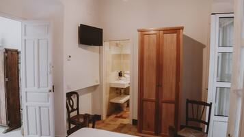 Un dormitorio con cama, armario de madera y televisor en la pared.
