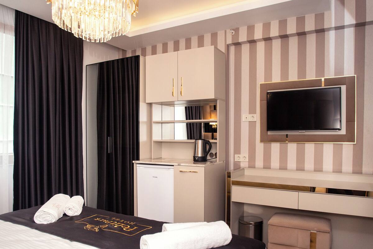 Una habitación de hotel moderna con una cama grande, un televisor de pantalla plana, un minibar y una zona de escritorio.