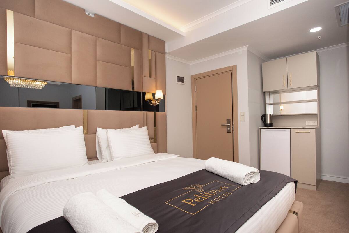 Habitación de hotel con una cama grande, un minibar y una kitchenette separada.