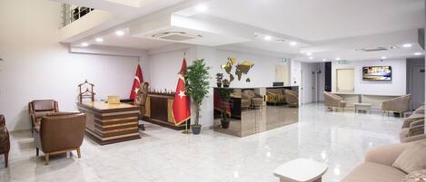 A spacious lobby with a reception desk, seating area, and a staircase.