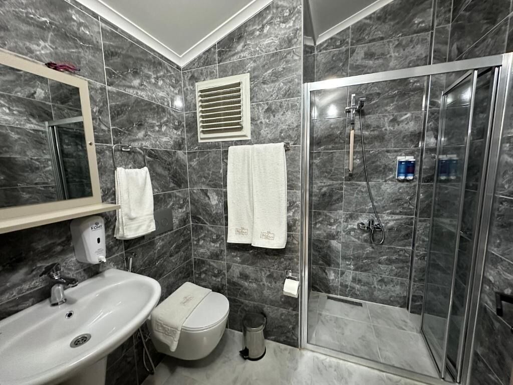 Un baño moderno con lavamanos, inodoro y zona de ducha.