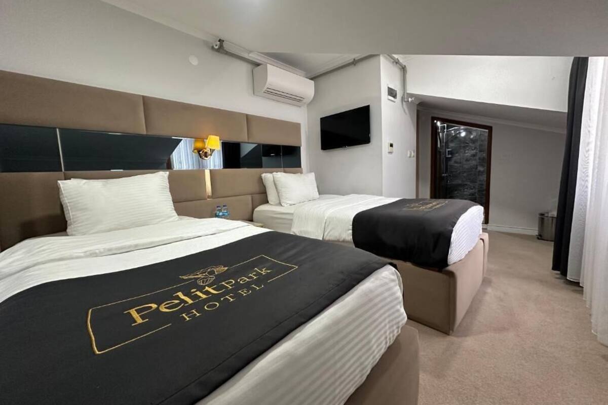 Habitación de hotel con dos camas, un televisor de pantalla plana y un equipo de aire acondicionado.