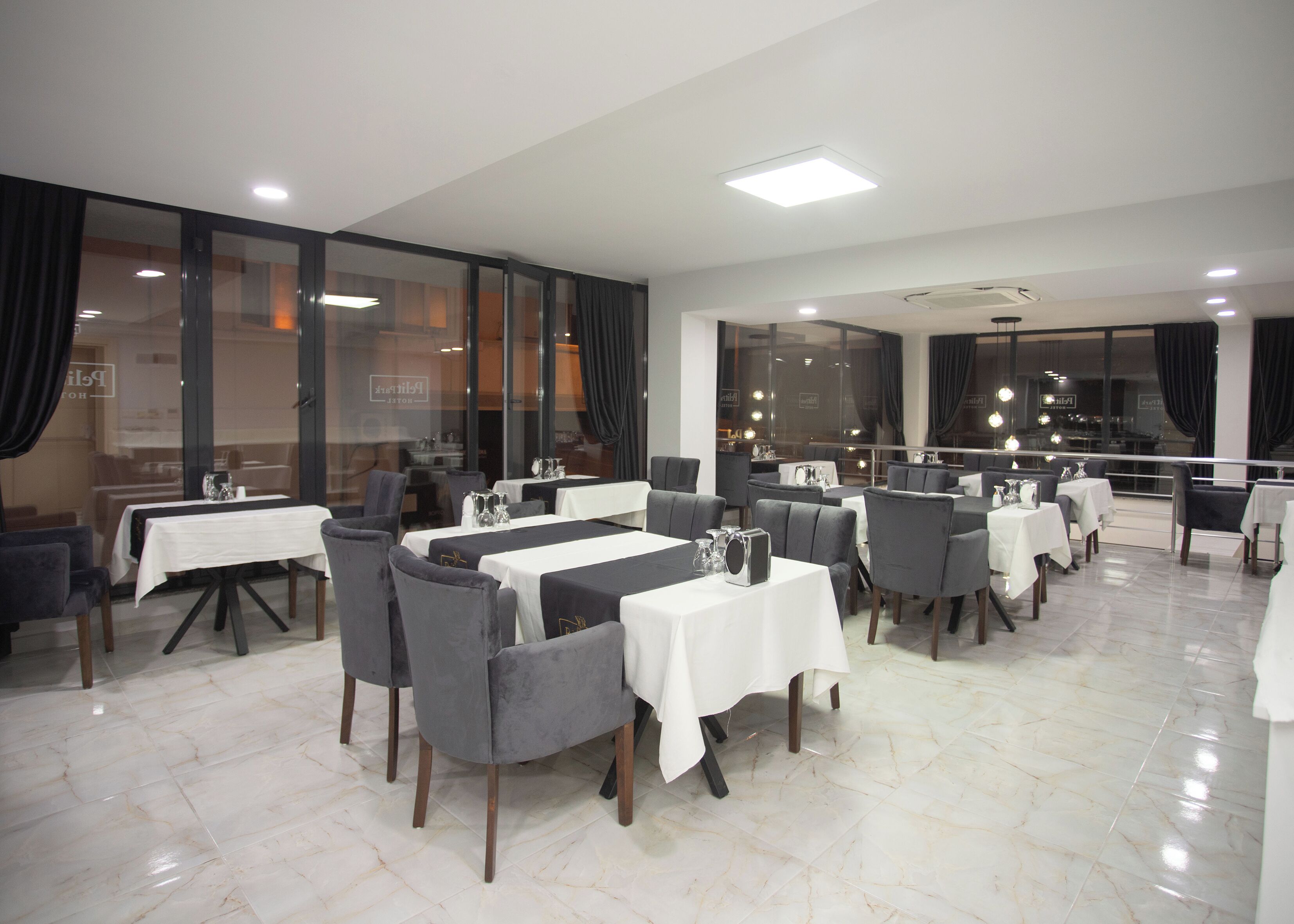 A restaurant with multiple tables and chairs, large windows, and a modern interior design.