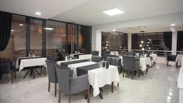 A restaurant with multiple tables and chairs, large windows, and a modern interior design.