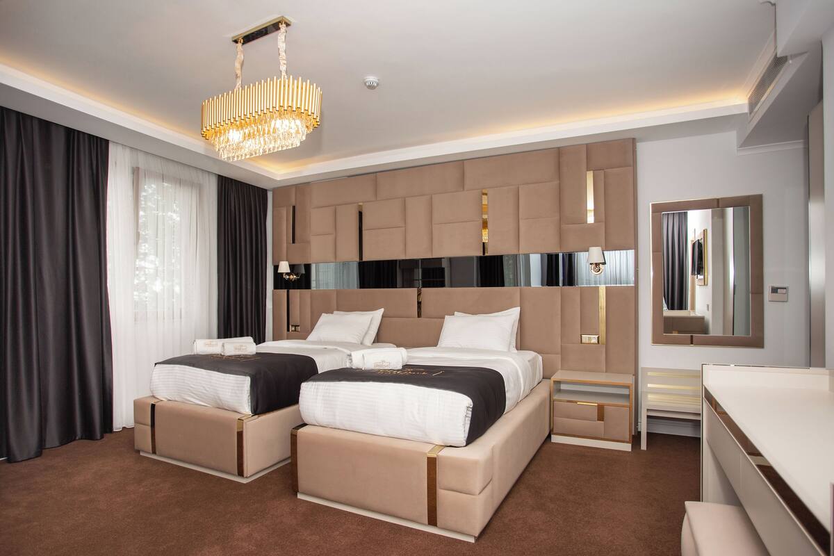 Una habitación de hotel moderna con una cama grande, un sofá cama independiente, un escritorio y un espejo amplio.