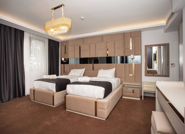 A modern hotel room with a large bed, a separate sofa bed, a desk, and a large mirror. - Pelit Park Hotel (Trabzon)