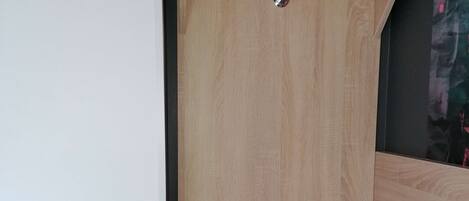 A wooden shower enclosure with a shelf above the door and a step leading into the shower.