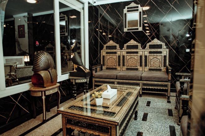 A room with a traditional sofa, a glass-top coffee table, and ornate wall decorations.