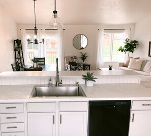 Una cocina moderna con una isla central, muebles blancos y un lavavajillas negro.