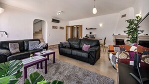 Een woonkamer met twee zwarte leren banken, een bijzettafeltje en een open haard.