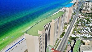 Un hotel costero con varios edificios altos, una playa y una carretera que bordea el océano.