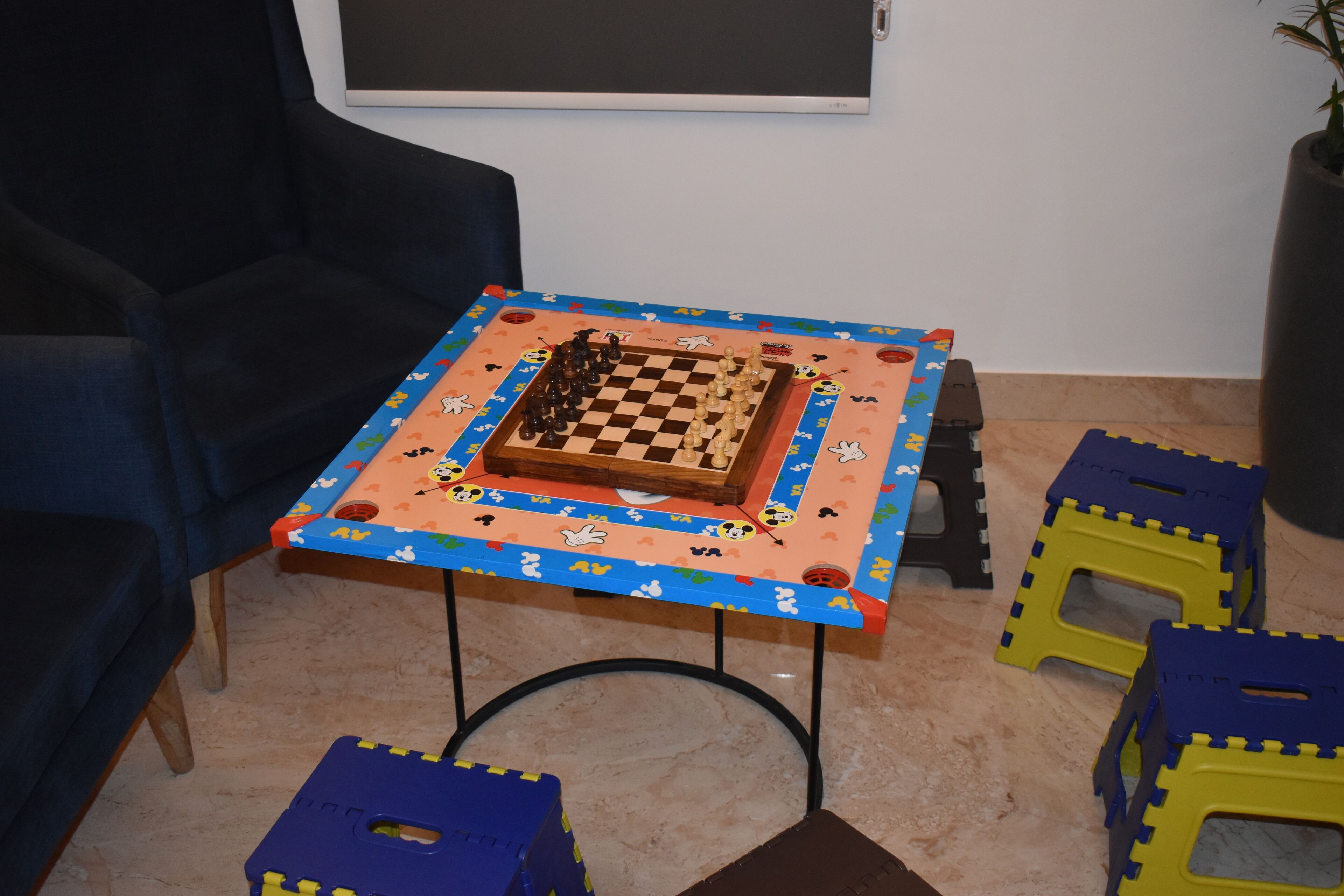 A room with a chess table, a blue armchair, and colorful play cubes.