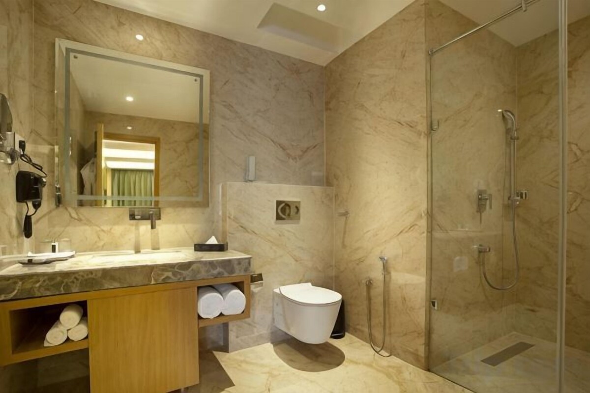 A modern bathroom with a marble vanity, a glass shower enclosure, and a toilet.
