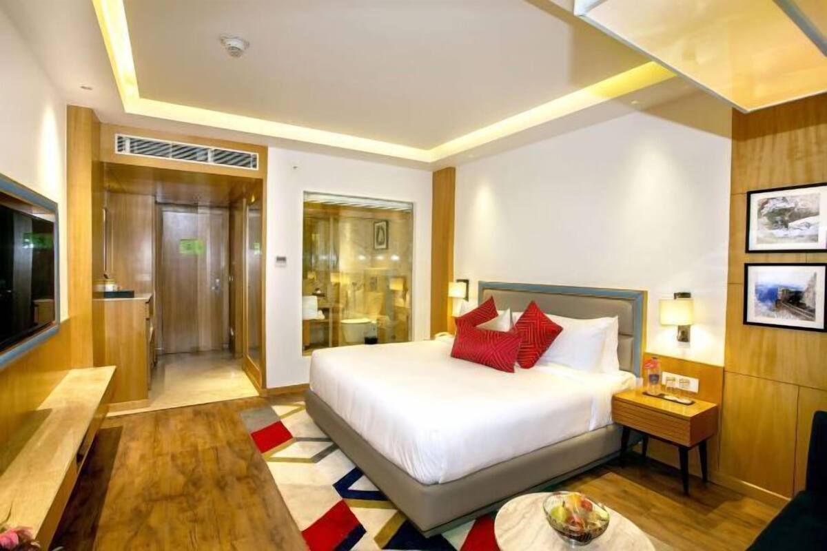 A hotel room with a bed, bedside table, lamp, and a television.