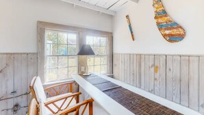 Een kamer met een lange tafel, houten stoelen, een raam en een lamp.