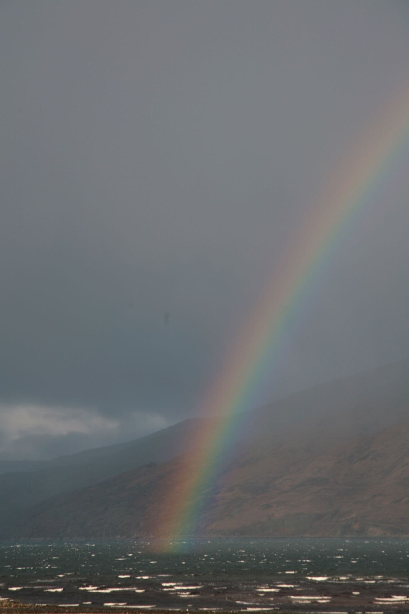 Een berglandschap met een duidelijke regenboog.
