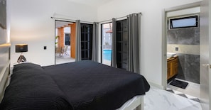 Um quarto com cama, escrivaninha e vista para uma piscina.