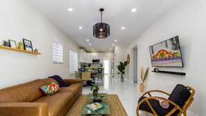 Una sala de estar moderna con un sofá de cuero marrón, un sillón de mimbre y una mesa de centro.