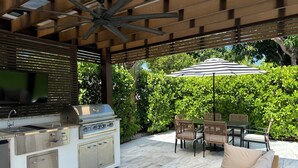 Un patio con una parrilla, asientos exteriores y un ventilador de techo.