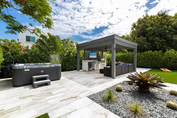 A covered outdoor kitchen area with a hot tub, barbecue, and seating. - Hot Tub BBQ Near Brickell W/ Free Parking (Miami)
