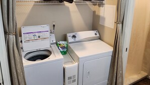 A laundry room with a washing machine, dryer, and shelves above for storage.