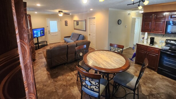 A living room with a round wooden table, two blue cushioned chairs, a brown sofa, and a television.
