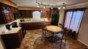 A kitchen with wooden cabinets, a round dining table, and a chandelier.