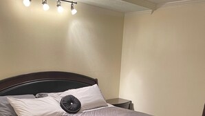 A neatly made bed with a quilted gray comforter, a decorative pillow, and a small plant.
