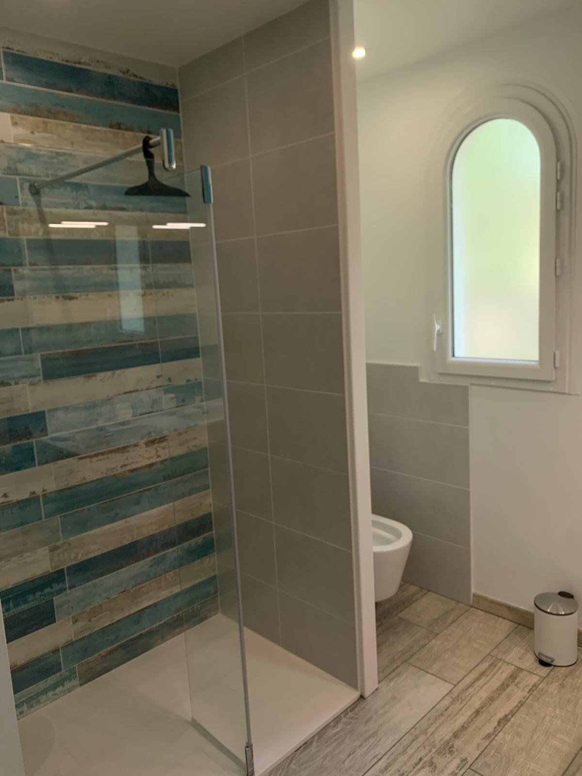 Ein Badezimmer mit Duschkabine, Toilette und Fenster.