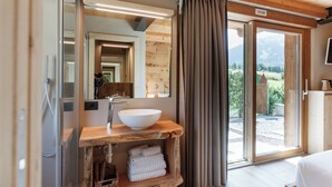 A wooden bathroom with a large mirror, a white sink, and a view of the outdoors. - AGRITURISMO SAN GALLO (Bormio)