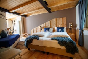 A bedroom with a wooden ceiling, a bed with a blue blanket, a wooden headboard, and a small bedside table with a lamp. - AGRITURISMO SAN GALLO (Bormio)