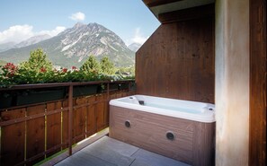A wooden deck with a hot tub, surrounded by a wooden fence and potted plants, overlooking a mountain. - AGRITURISMO SAN GALLO (Bormio)