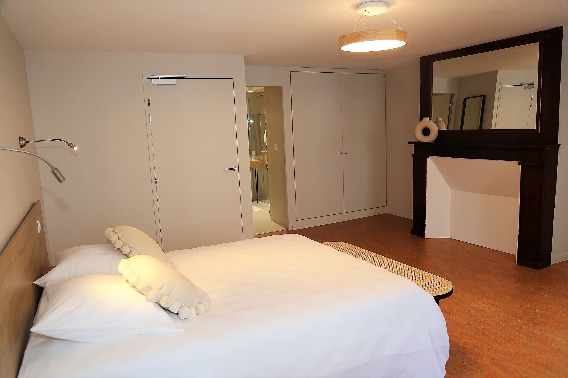 Ein Schlafzimmer mit einem Bett, einem Kleiderschrank, einem Spiegel und einem kleinen Tisch.