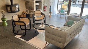 Un rincón acogedor con chimenea de piedra, muebles de mimbre y vistas a la calle.
