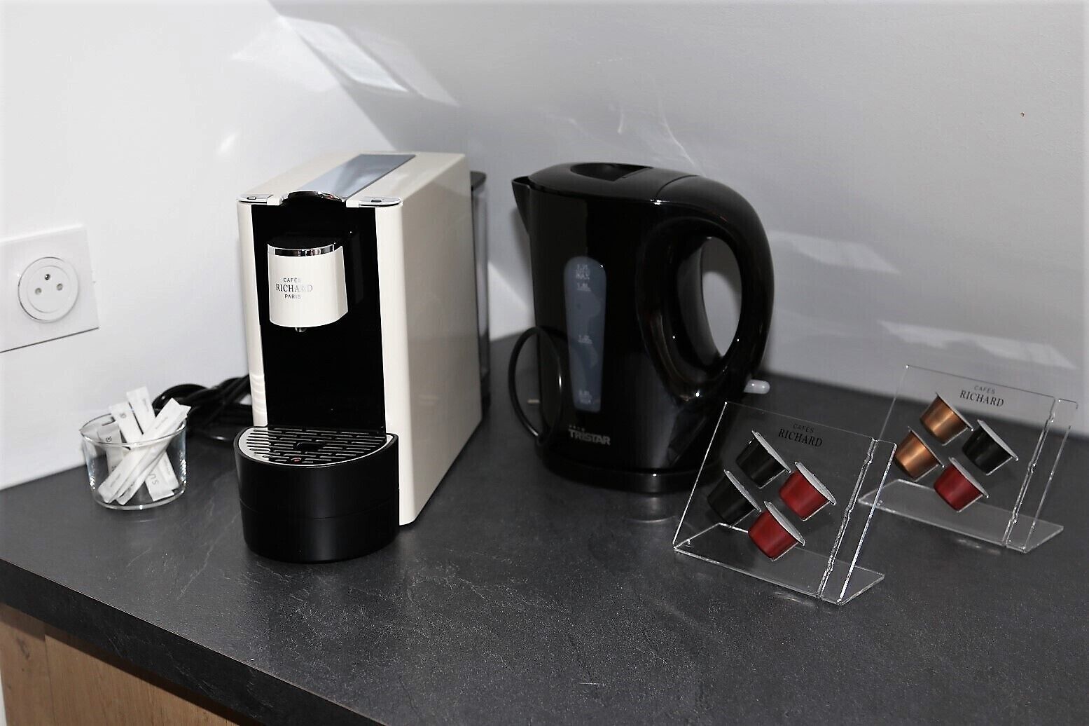 A coffee machine, a coffee pod display, and a coffee maker on a kitchen counter.