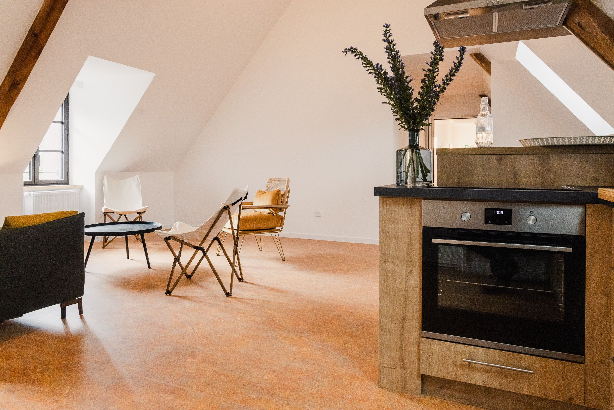 Een moderne keuken met een inbouwoven en een eethoek met een tafel en stoelen.