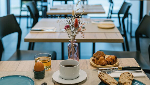 Desayuno preparado para dos personas, con croissants, pan, café y jugo.